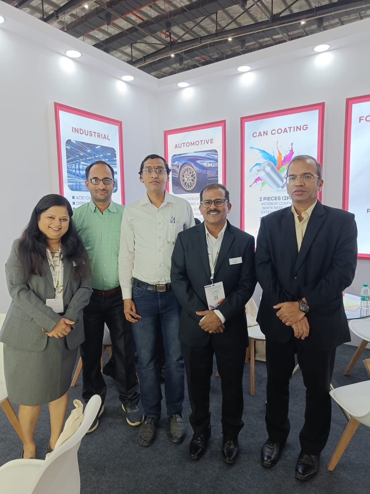 Colorina technical and sales team standing in front of automotive and can coating product display boards at the expo.